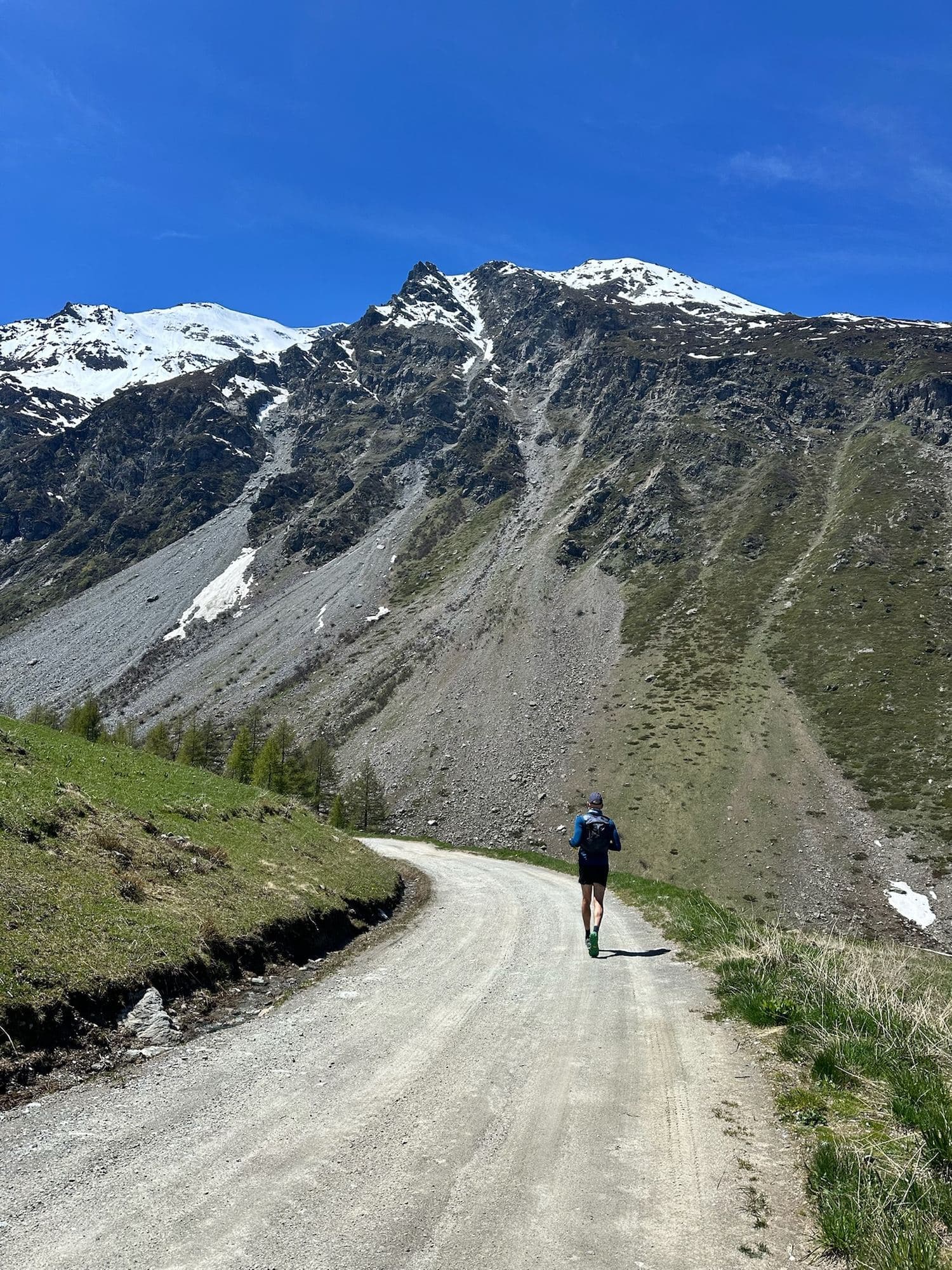 A trail runner on a gravel track towards snow-capped mountains