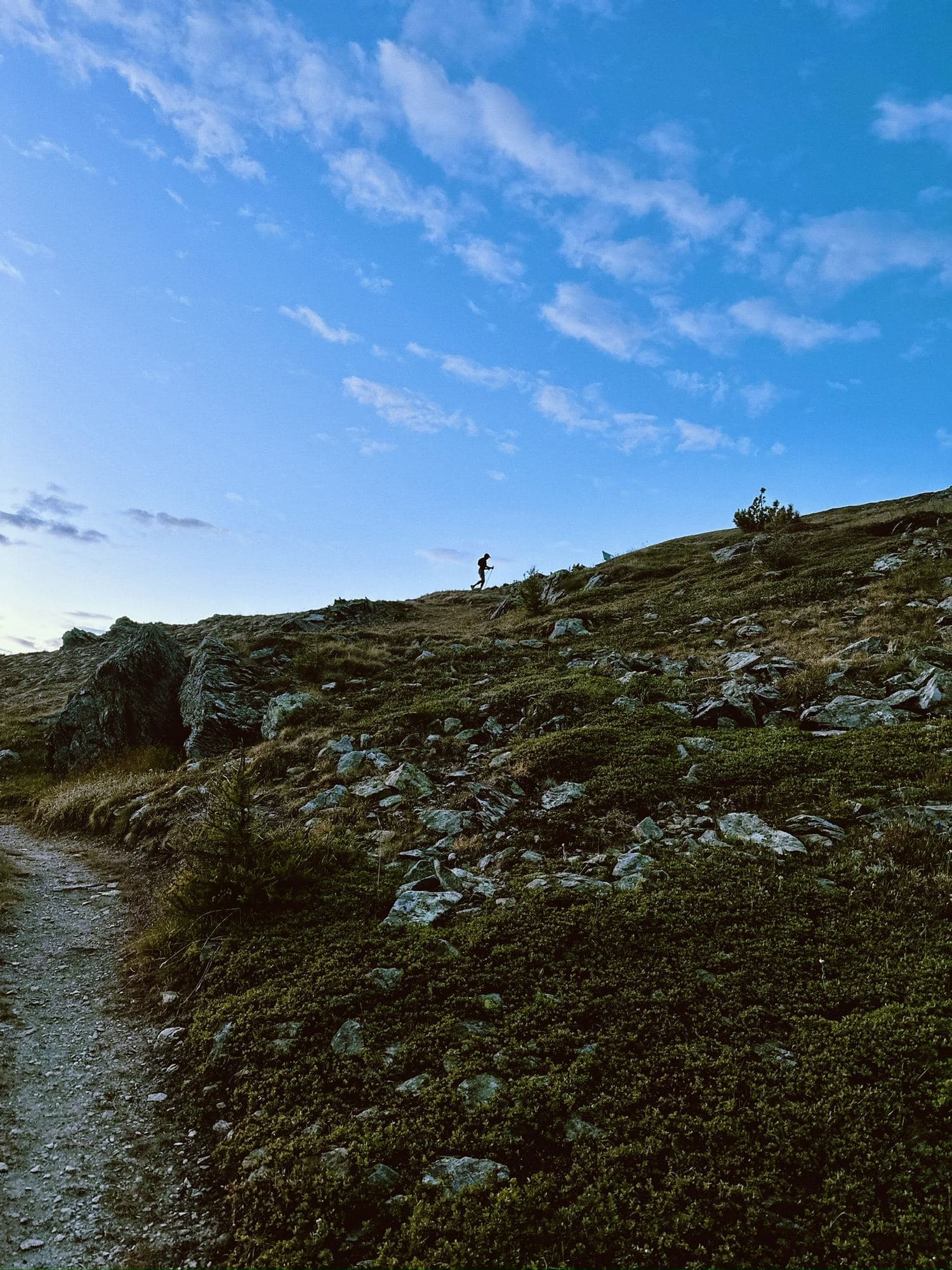 A trail runner on a high ridge path under a wide sky